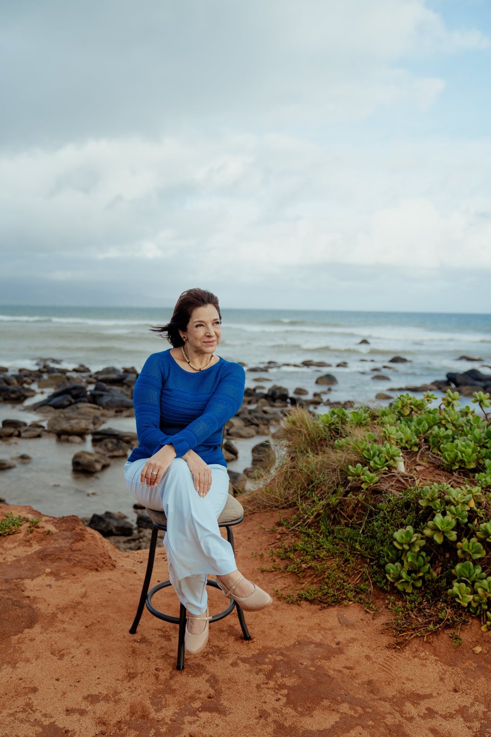 Sandra Gat sentada frente al mar en Maui, con suéter azul